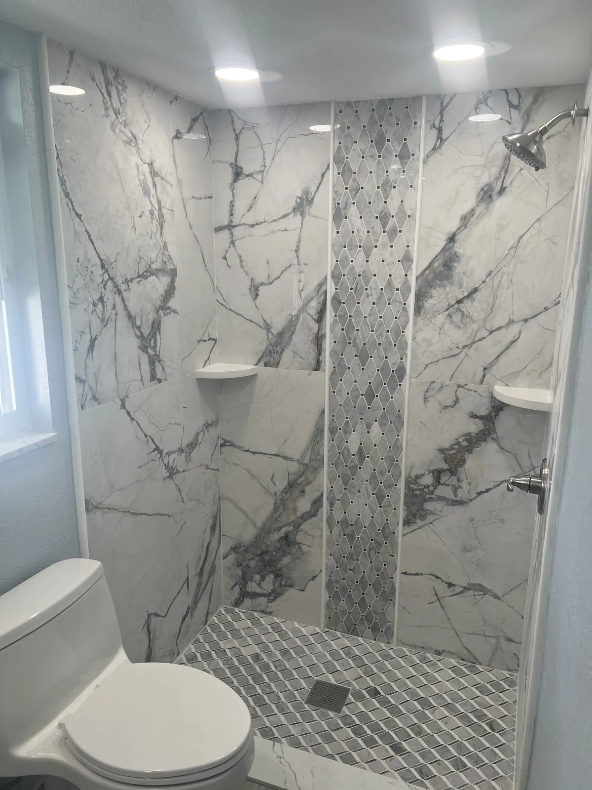 Marble Walk-In Shower — Book-matched porcelain slab walls with a diamond mosaic inlay, marble mosaic floor, and polished chrome rainfall fixtures.